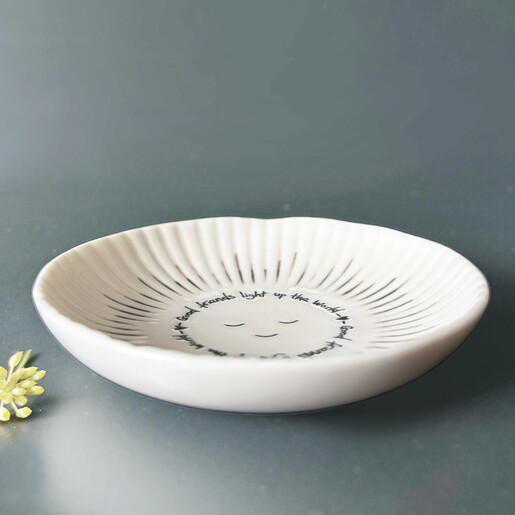 Side angle of fluted white ceramic trinket dish with etched sun design
