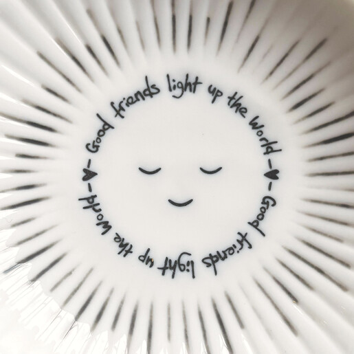 Close-up of white ceramic trinket dish reading good friends light up the world