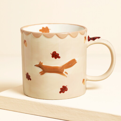 Ceramic cream mug featuring a raised running fox design and autumn leaves