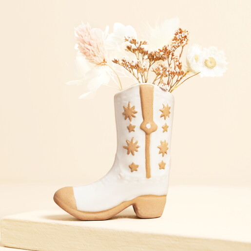 Cream ceramic cowboy boot bud vase holding delicate dried flowers