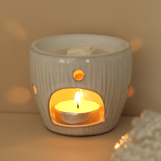 Close-up of glowing candle flame inside ceramic acorn wax burner