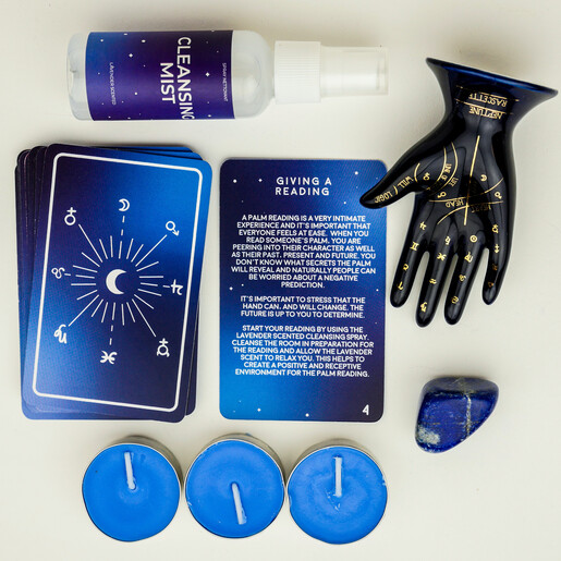 Flat lay display of palmistry instructional cards, ceramic hand, tealights, and mist