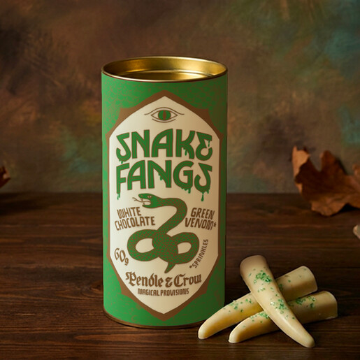 White chocolate snake fangs with green sprinkles next to an illustrated green tin tube