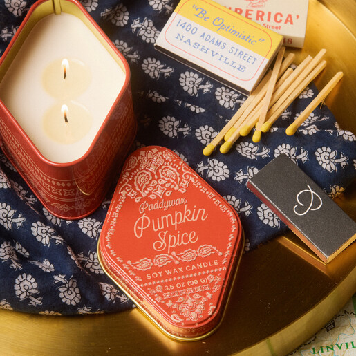 Open lit two-wick pumpkin spice soy wax candle alongside matching bandana print lid