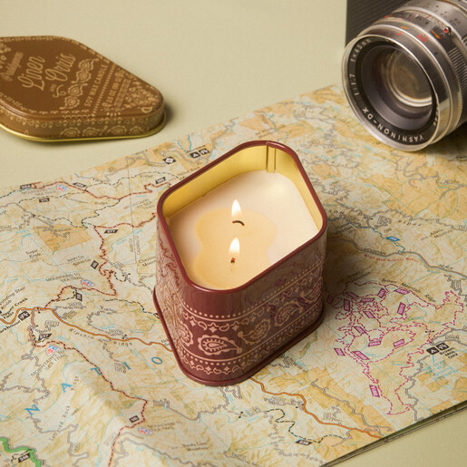 Lit two-wick Paddywax pomegranate spruce candle glowing on a vintage map