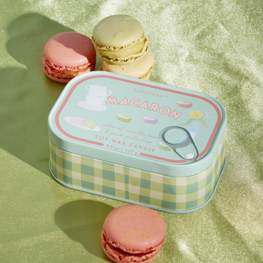 Paddywax Macaron tin candle styled next to colourful French macarons on green fabric