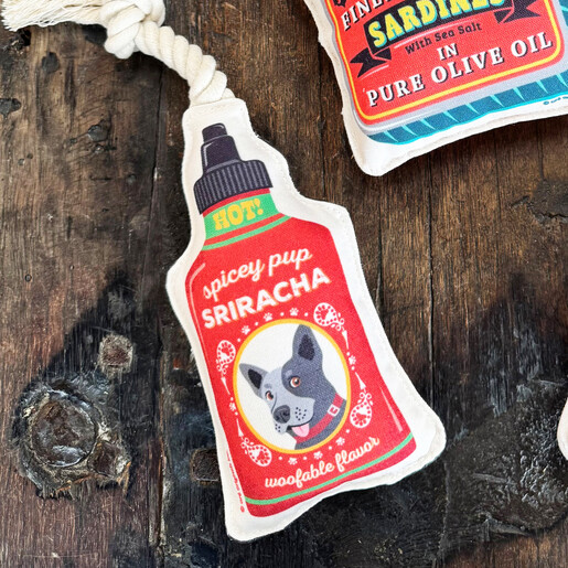 Novelty sriracha hot sauce dog toy styled on a wooden surface