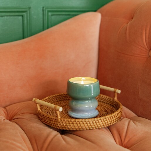 Paddywax ombre scented candle displayed on a woven wicker tray atop an armchair