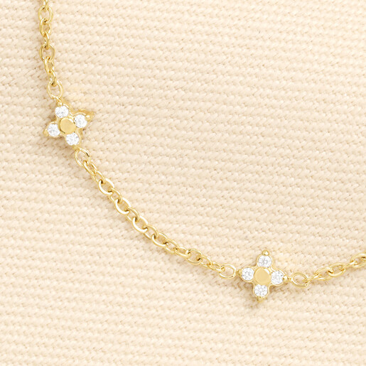Detailed close-up of a crystal-studded clover station charm on a gold chain
