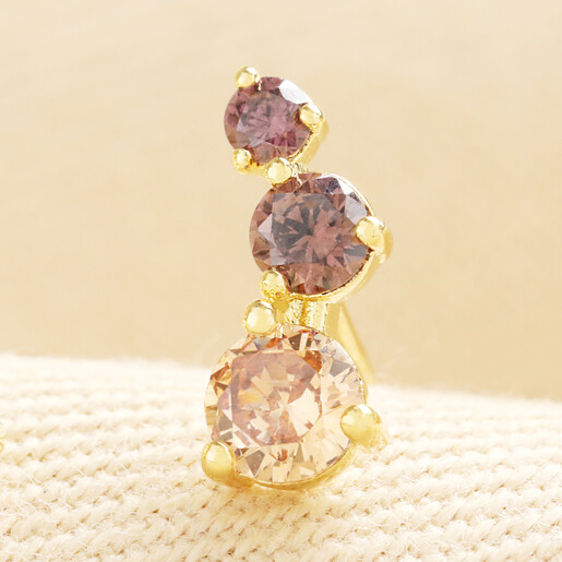 Close up of single gold climber stud earring set with graduating brown crystals