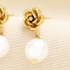 Detailed view of rose gold rose stud with smooth white pearl drop.