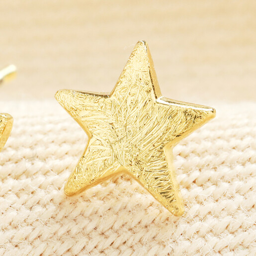 Close up of the textured brushed gold star stud earring.