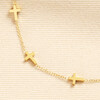 Close up of small gold cross charms on a fine gold stainless steel chain