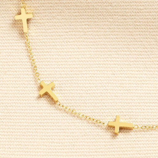 Close up of small gold cross charms on a fine gold stainless steel chain