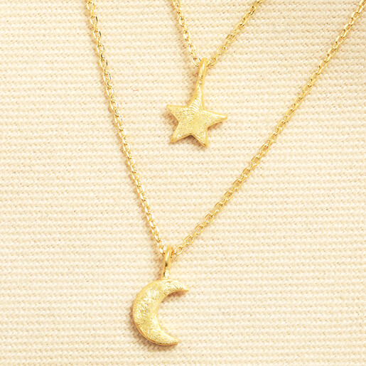 Close up of gold brushed star and crescent moon charms on delicate chains