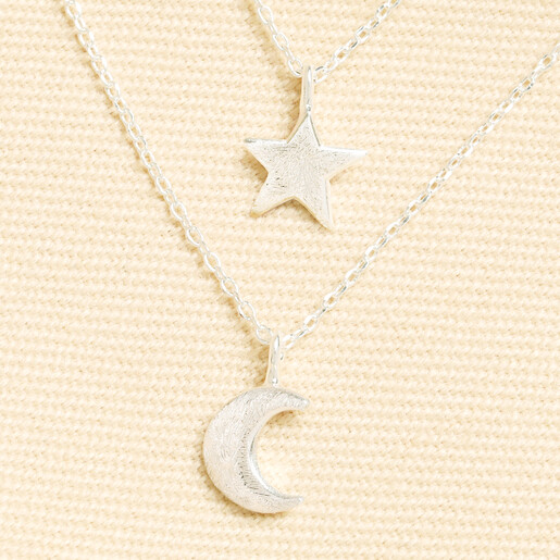 Close-up of silver brushed star and crescent moon charms on delicate double chains