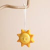 Ceramic sun hanging decoration with smiling face suspended from branch by ribbon