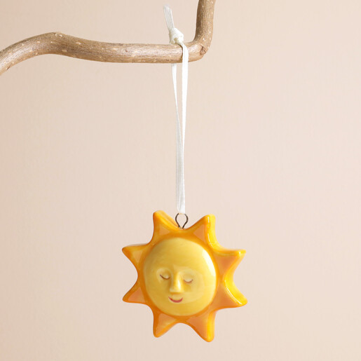 Ceramic sun hanging decoration with smiling face suspended from branch by ribbon