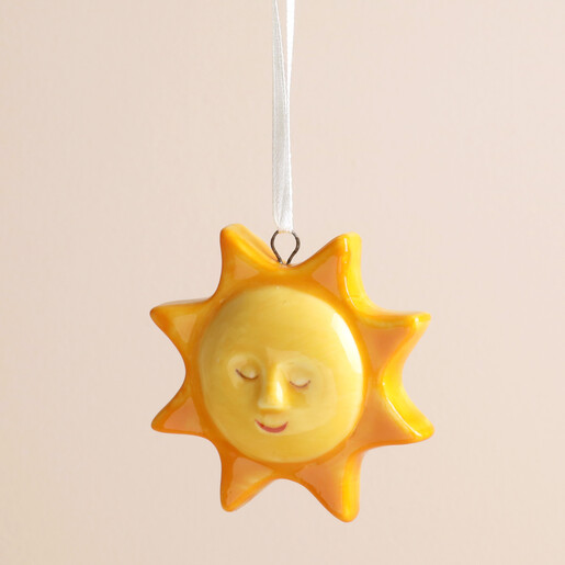 Close-up of glossy yellow ceramic smiling sun face hanging decoration