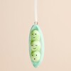 Close-up of glazed ceramic pea pod decoration showing three cute smiling peas