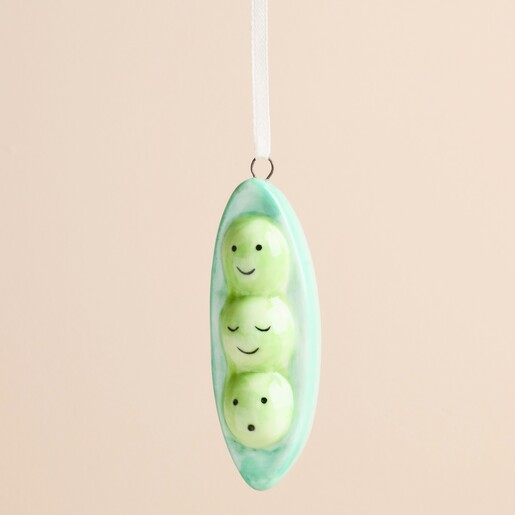 Close-up of glazed ceramic pea pod decoration showing three cute smiling peas