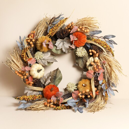 autumn-themed decorative wreath against a pale pink background
