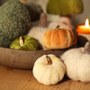 Assorted colourful velvet and plush pumpkin decorations displayed with a wooden bowl and candle.