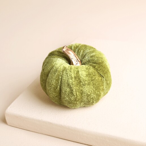 Mini green velvet pumpkin decoration with shiny gold stem on a neutral stand.