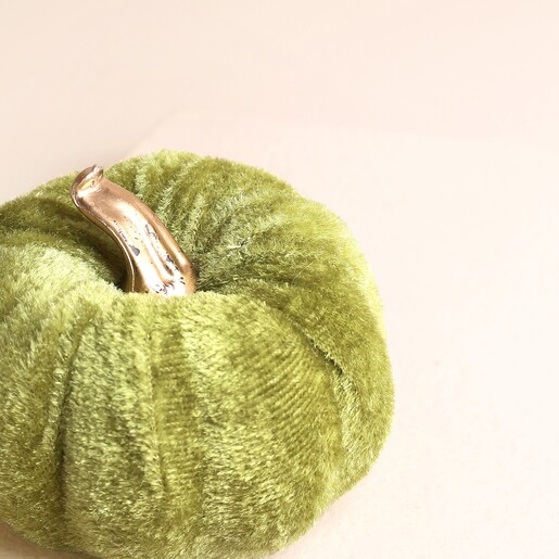 Close up of mini green velvet pumpkin showing soft ribbed fabric detail.