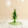 Close-up of sculpted green Christmas tree stem with colourful raised baubles on coupe glass
