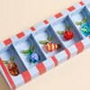 Close-up of glass turtle, fish, lobster and crab charms in box.