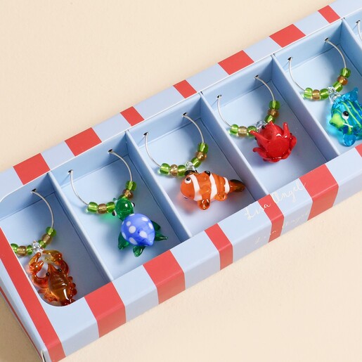 Close-up of glass turtle, fish, lobster and crab charms in box.