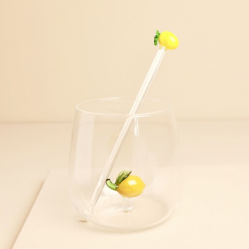 Glass lemon cocktail drink stirrer standing inside a clear glass tumbler with lemon detail