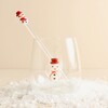 Glass snowman cocktail stirrer inside a matching snowman tumbler on faux snow