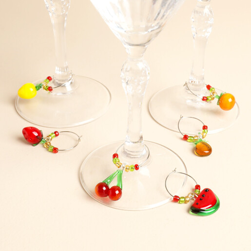 Beaded fruit charms fastened onto the stems of glassware drinks glasses.