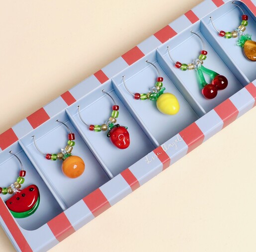 Close-up of vibrant glass fruit wine charms in a striped gift box.