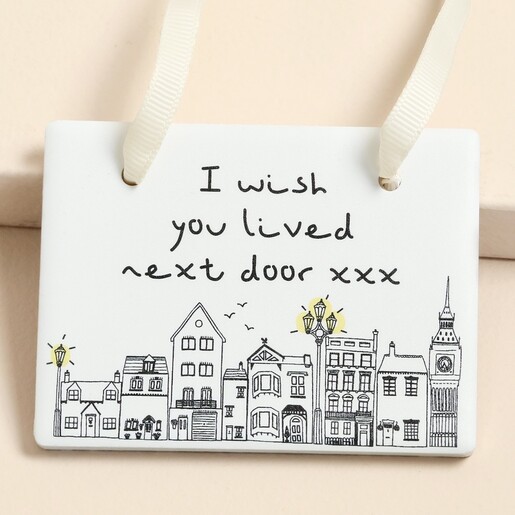 Close-up of ceramic plaque featuring I wish you lived next door quote