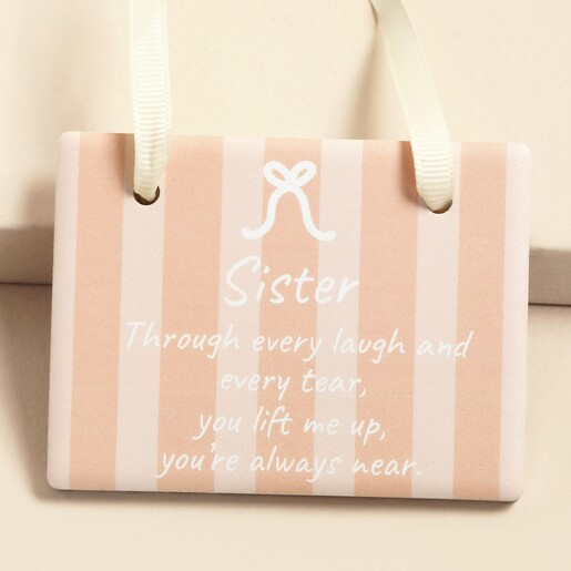 Close up of ceramic hanging plaque with bow motif and sentimental sister wording