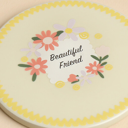 Close-up of Beautiful Friend ceramic coaster with floral motif and yellow wavy edge