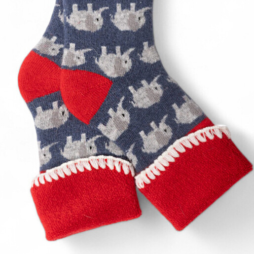 Close-up of blue knitted elephant socks with red cuffs and blanket stitch detail