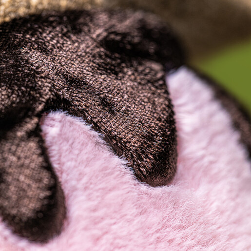 Macro detail of rich brown chocolate drip on fluffy pink marshmallow plush