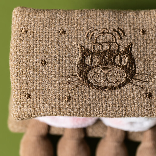 Close-up of embroidered biscuit top featuring a cat illustration on textured fabric