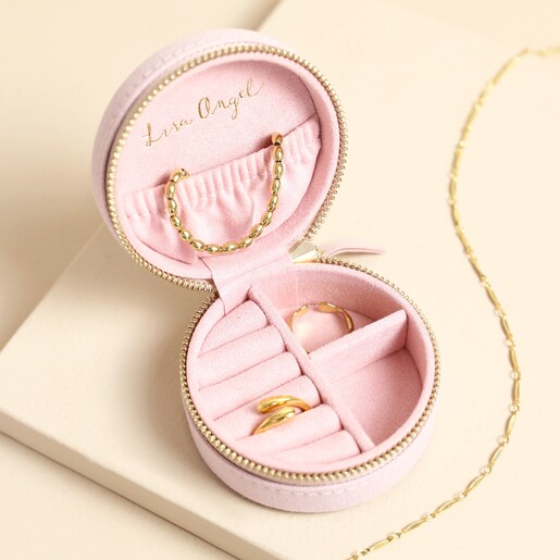 Open pink jewellery case showing interior ring rolls and compartments holding gold jewellery