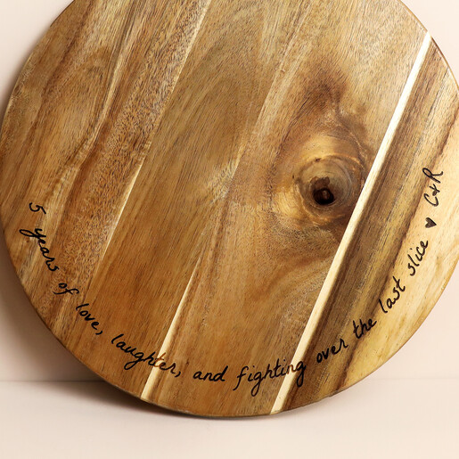 Close up of engraved anniversary message on round wooden serving board