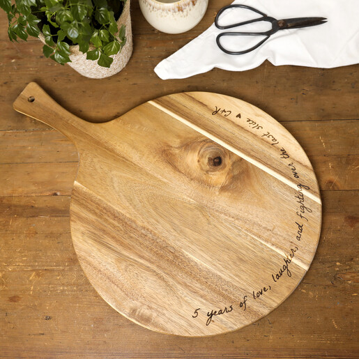 Personalised round wooden 5 year anniversary serving board with handle on a table