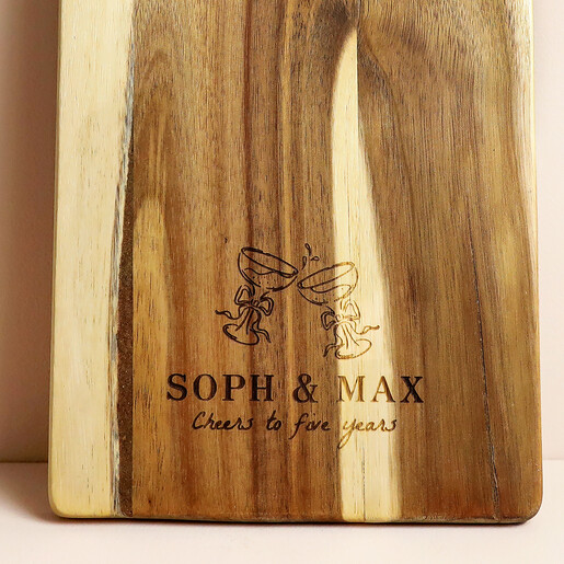 Close up of engraved clinking glasses motif and custom anniversary text on wood