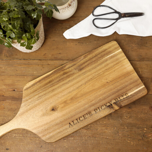 Personalised wooden paddle board engraved with Alice's Picky Bits on a wooden table