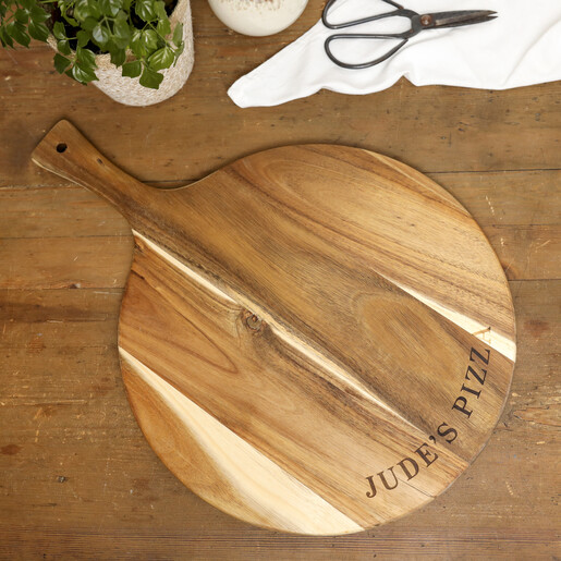 Flat lay of personalised wooden pizza board on a rustic wooden tabletop