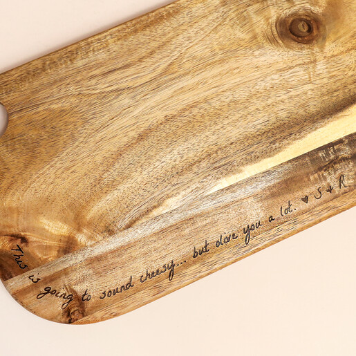 Close-up of engraved handwritten message on an acacia wood serving board
