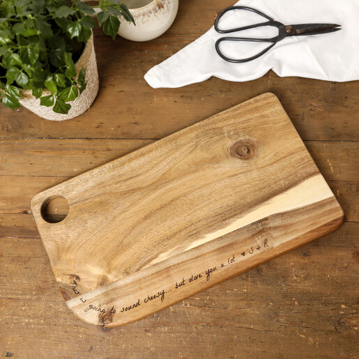 Personalised acacia wood serving board engraved with message on a wooden tabletop